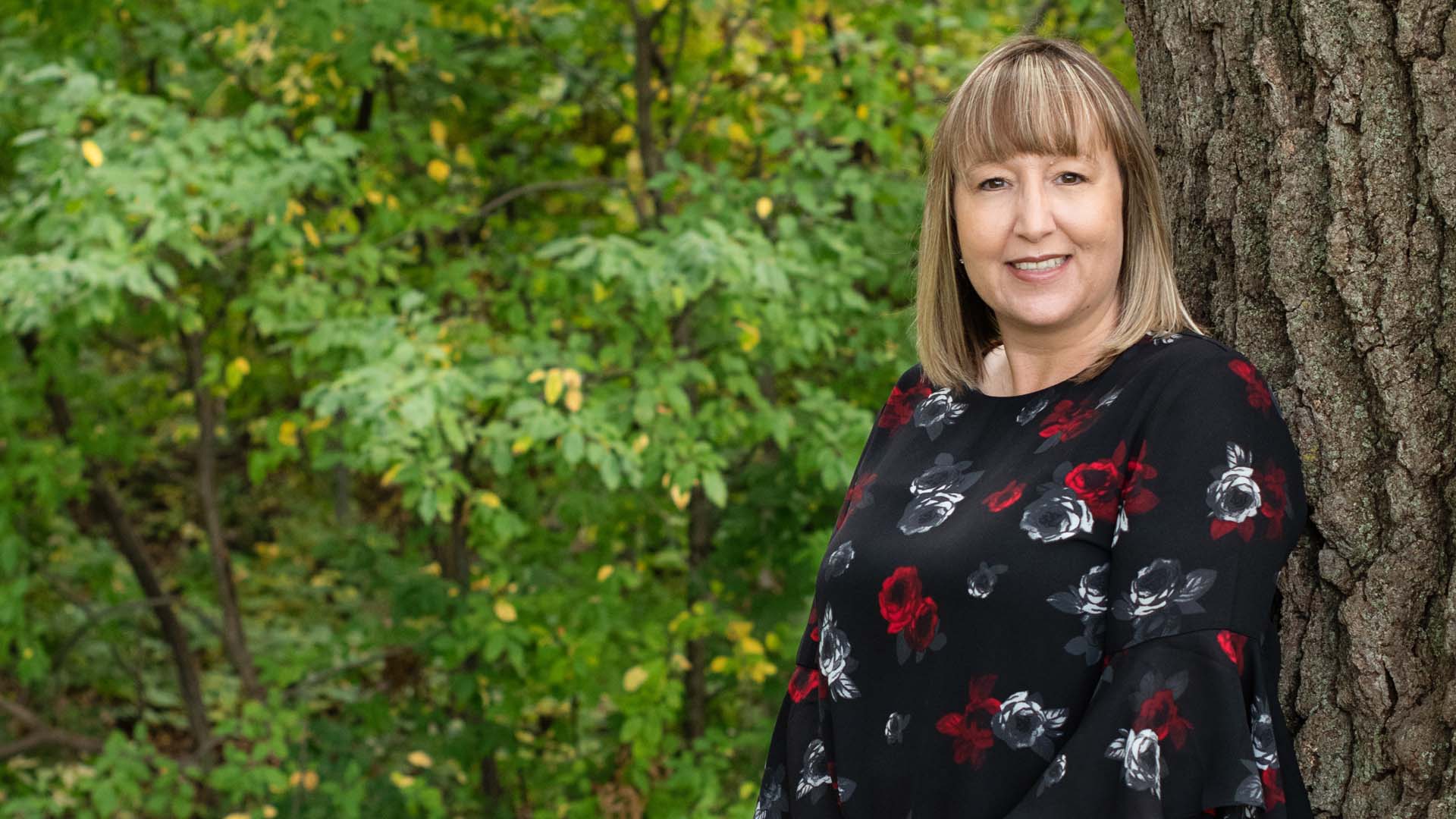 Karen Knightly standing next to a tree in a park