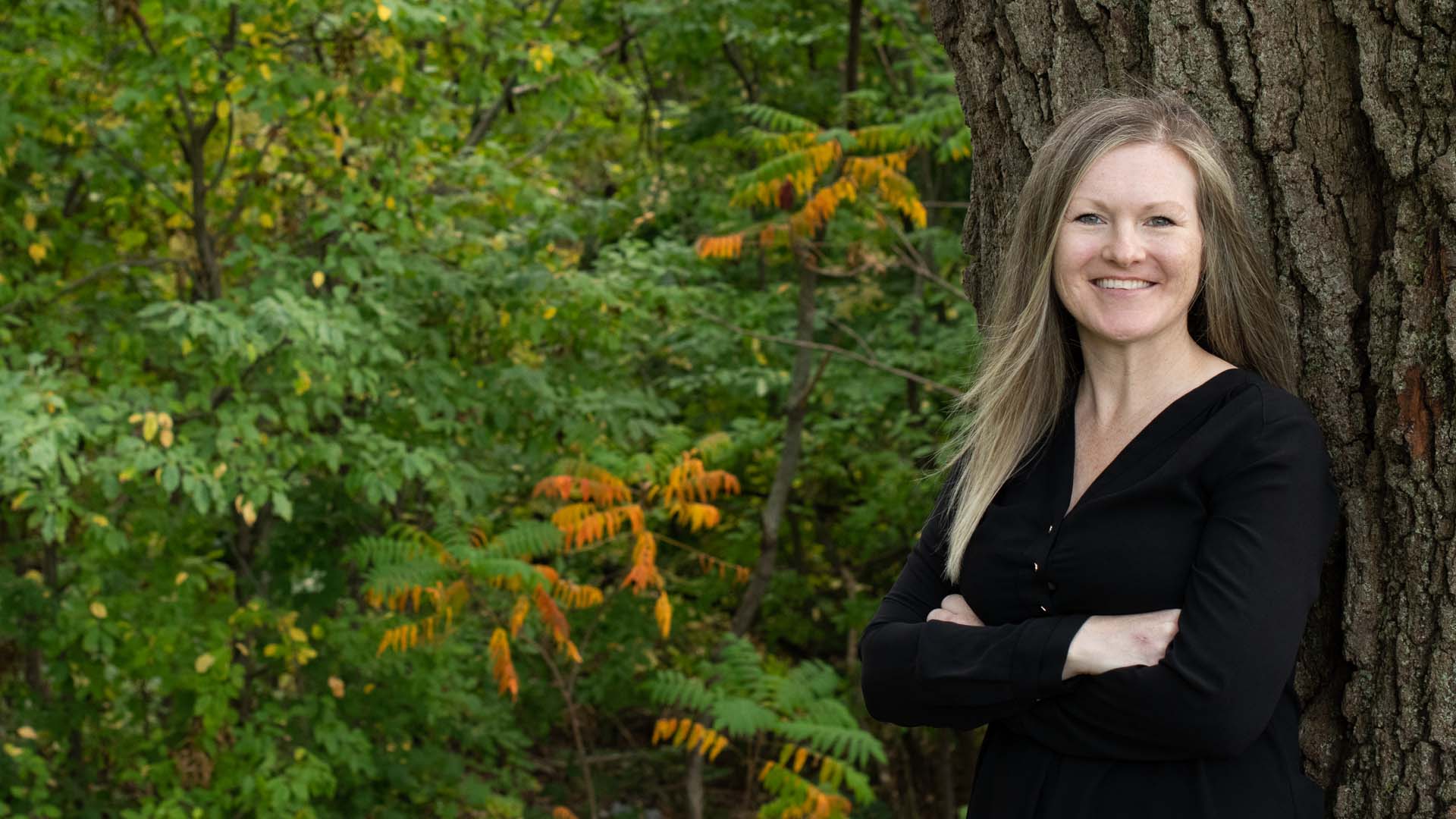 Melissa Diamond leaning against a tree in a park